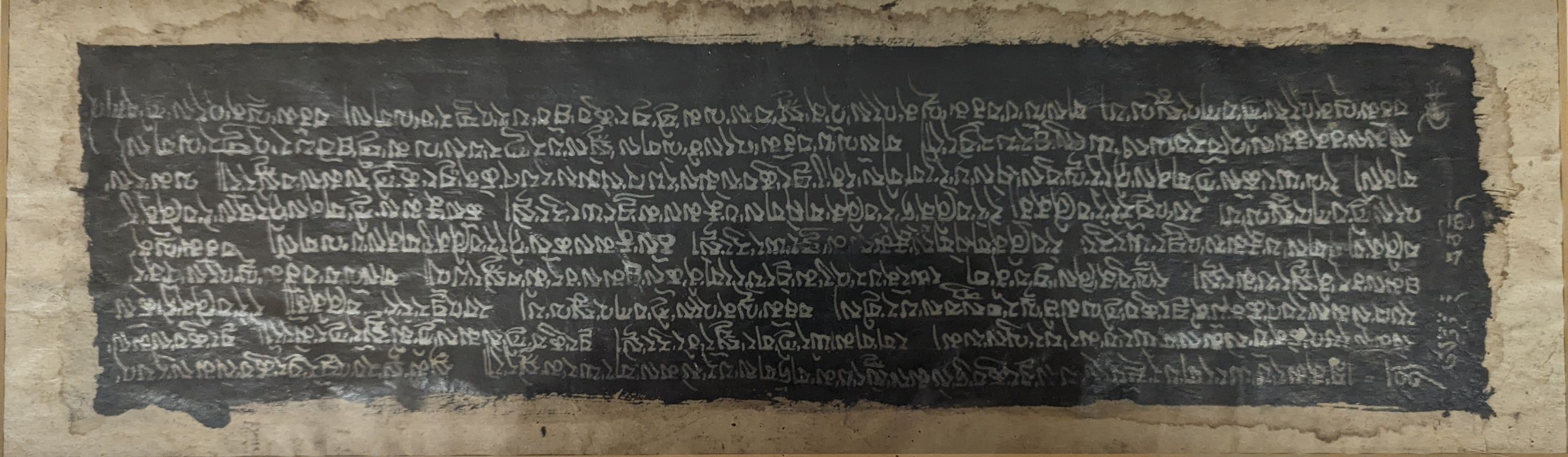 A framed Tibetan Sanskrit sutra panel, 45cms x 13 cms.